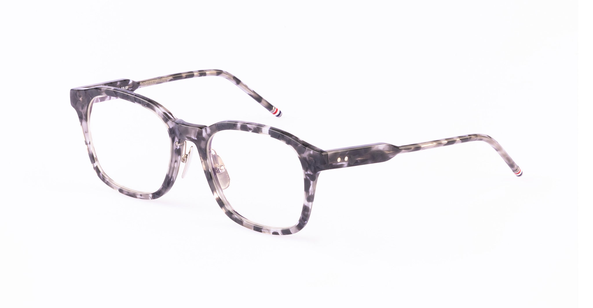 Thom Browne 934 eyeglasses with clear tortoiseshell rectangular frames and thin patterned arms, shown from a side angle.