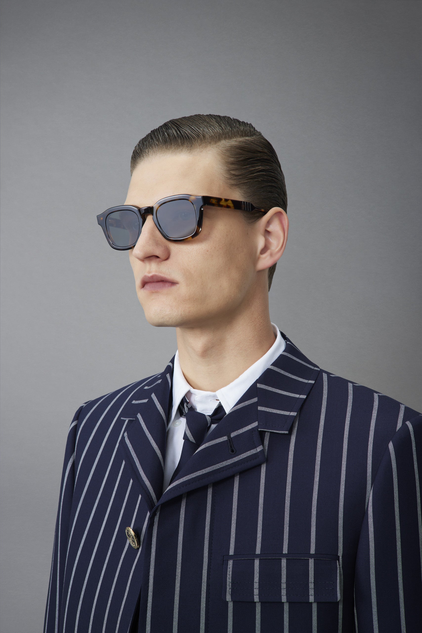 Model with slicked hair and striped suit wearing Thom Browne 412 Sunglasses in Honey Tortoise, angled view