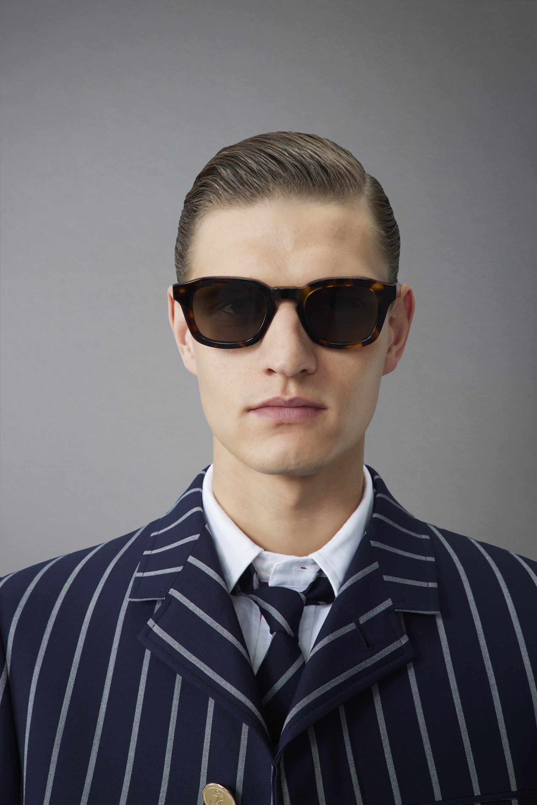 Man wearing Thom Browne 412 sunglasses and a pinstripe suit, facing forward and looking at the camera.