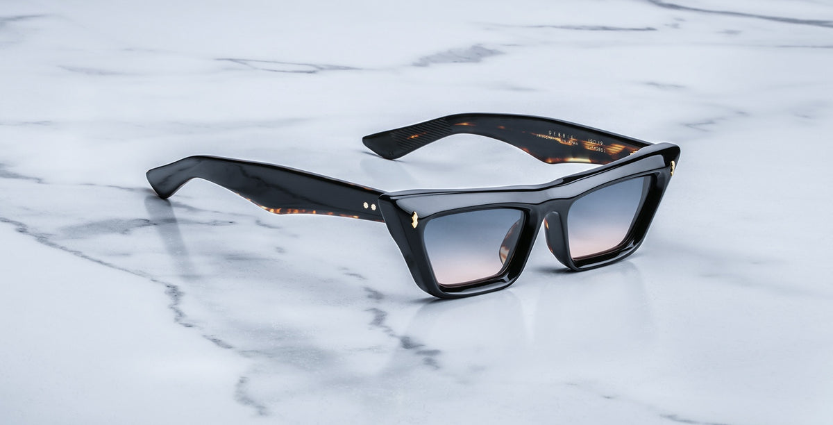 Jacques Marie Mage Debbie in Noir acetate cat-eye frame with gradient gray lenses, featuring gold arrowhead pins and sculpted temples with exposed wirecore