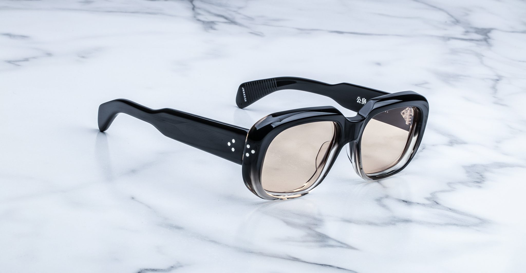 Jacques Marie Mage Kobo black square sunglasses with thick frames and brown gradient lenses, shown from above.
