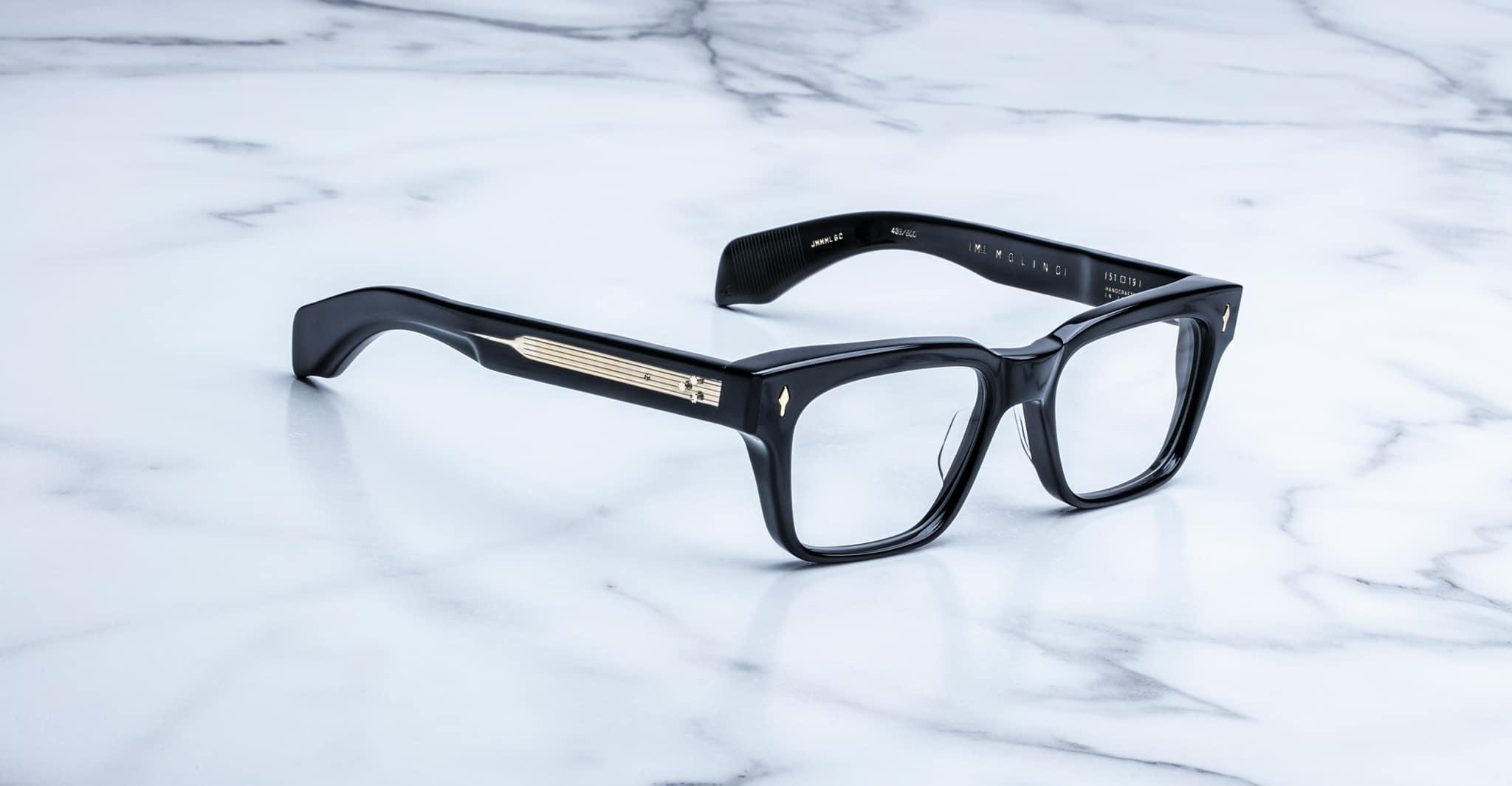 Jacques Marie Mage Molino black rectangular eyeglasses, thick frames, gold-accented arms, shown from above angle.