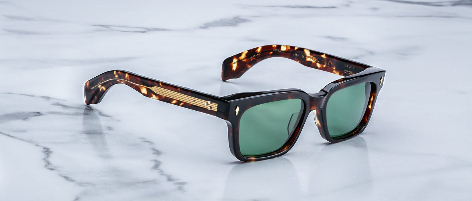 Jacques Marie Mage Molino 55 sunglasses featuring green lenses and gold accents, shown from above.