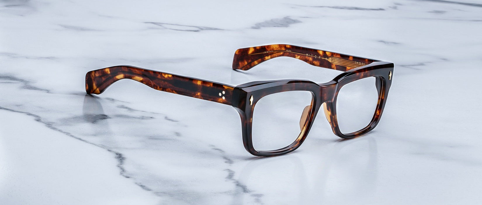 The Jacques Marie Mage Torino features bold, handcrafted rectangular acetate frames by Jacques Marie Mage, displayed on a white marble surface.