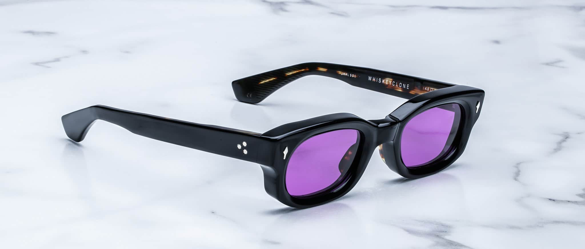 Jacques Marie Mage Whiskeyclone sunglasses with thick frames and purple lenses, top view.