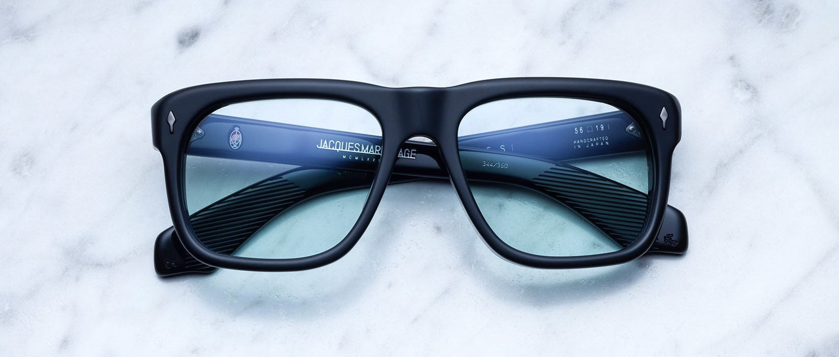 Jacques Marie Mage Yves black rectangular eyeglasses with blue-tinted lenses, shown from above.
