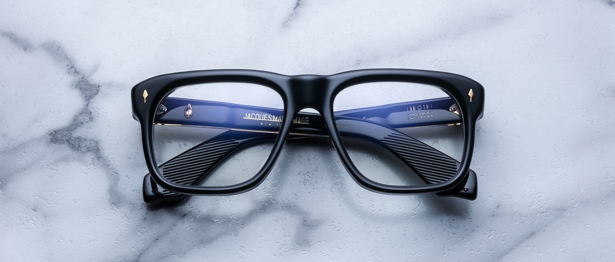 Jacques Marie Mage Yves black rectangular eyeglasses with blue temples, top view.