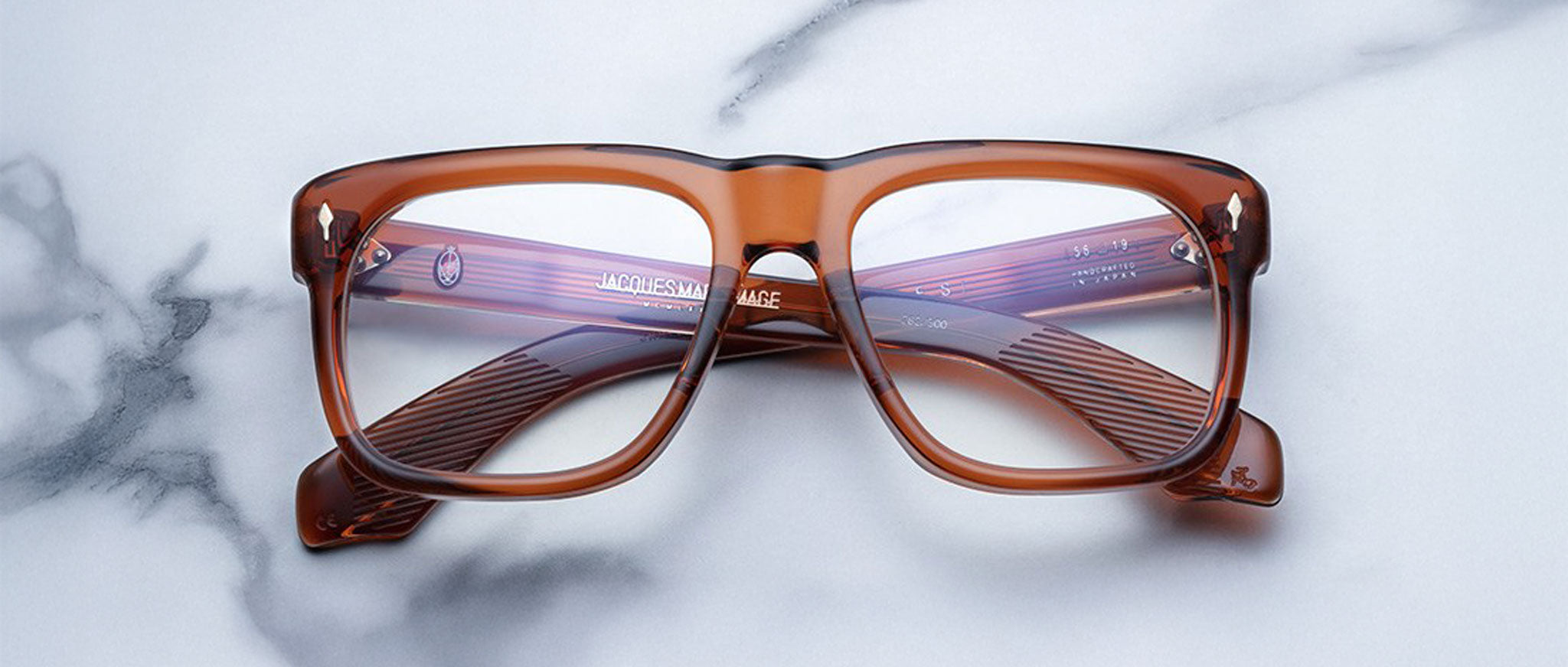 Jacques Marie Mage Yves in Rootbeer optical, rectangular translucent brown acetate frame with warm amber tones, clear lenses, and signature arrowhead rivets, front view with visible engraved wirecore temples