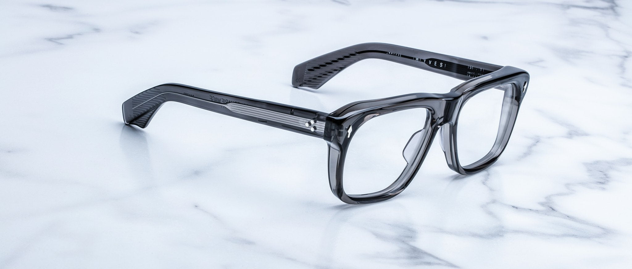 Jacques Marie Mage Yves translucent gray rectangular eyeglasses, top view, displayed on a surface.