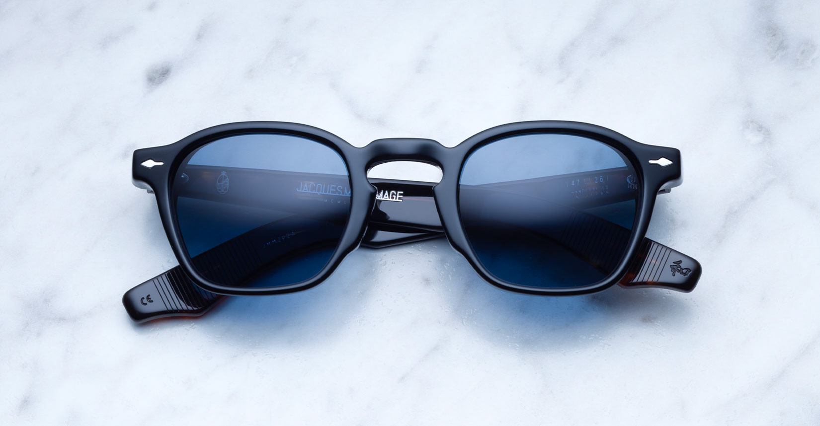 Jacques Marie Mage Zephirin 47 sunglasses with black frames and blue lenses shown from above.