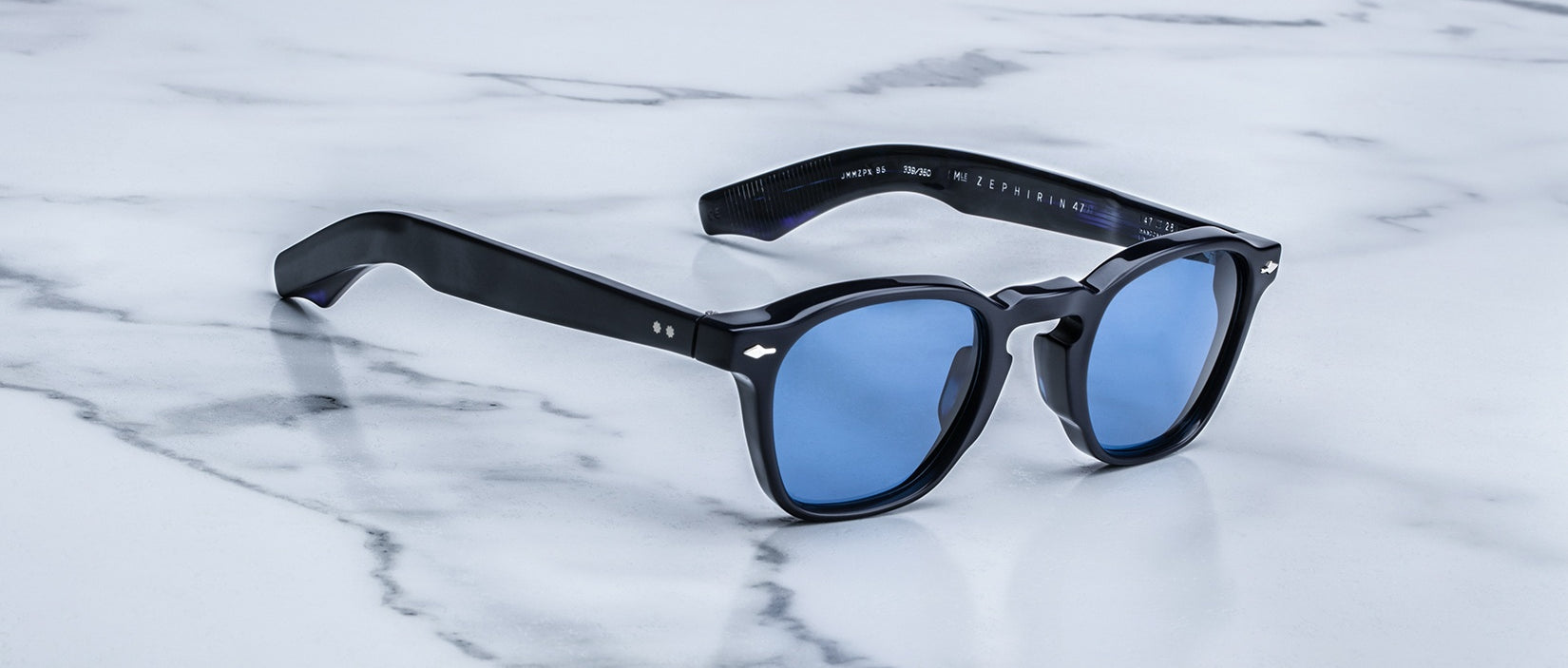 Jacques Marie Mage Zephirin 47 sunglasses with blue lenses shown from above on a flat surface.