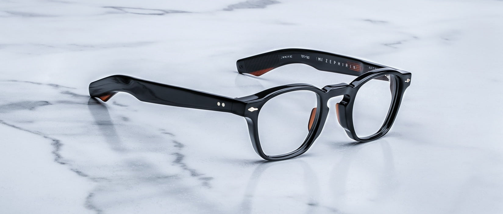 A pair of Jacques Marie Mage Zephirin eyeglasses by Jacques Marie Mage rests elegantly on a white marble surface.
