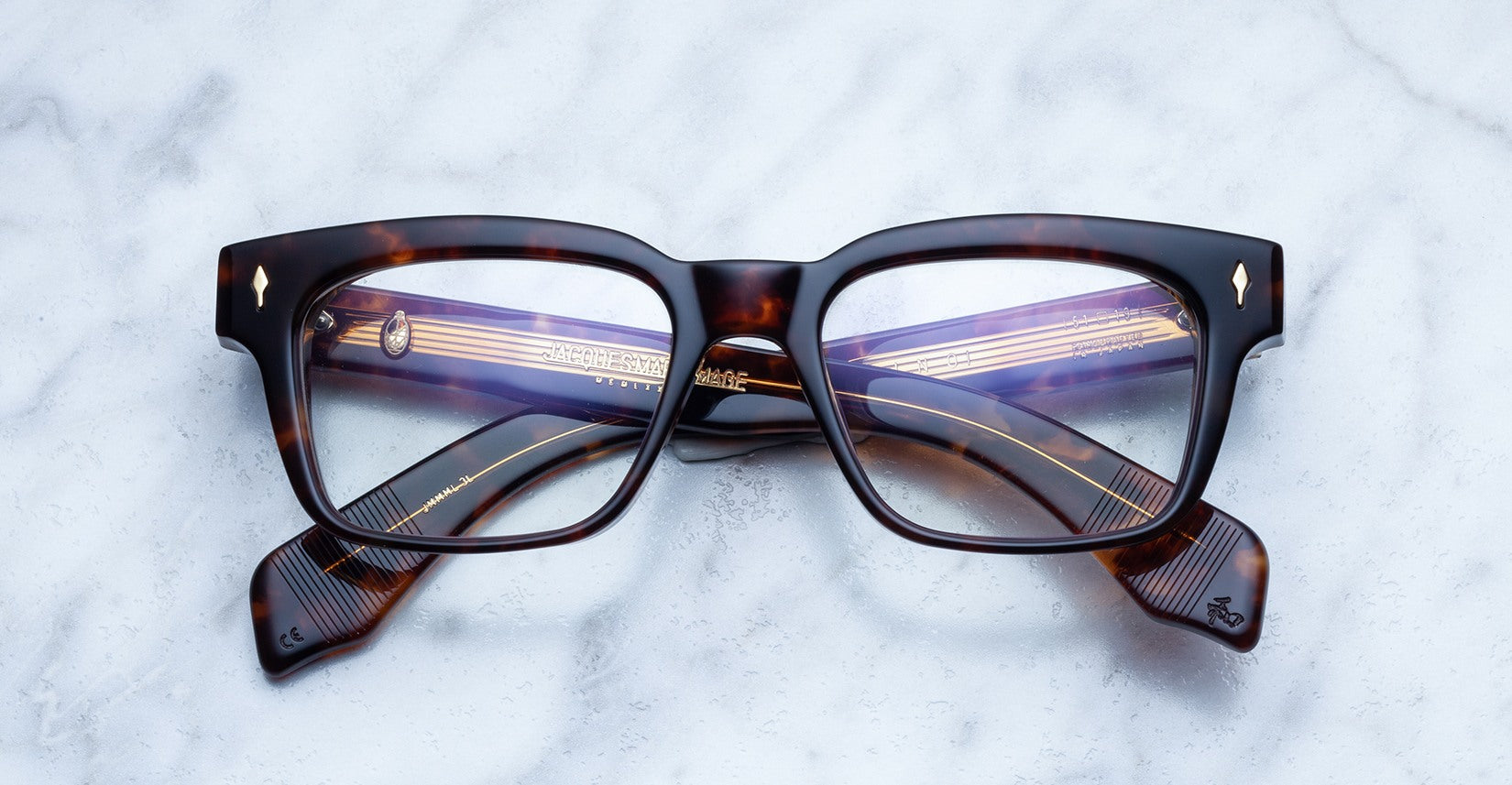 Jacques Marie Mage Molino rectangular tortoiseshell eyeglasses with gold-detailed arms, top-down view.