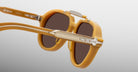 Close-up of Jacques Marie Mage 1991 sunglasses, mustard yellow frame, dark lenses, and metallic accents.