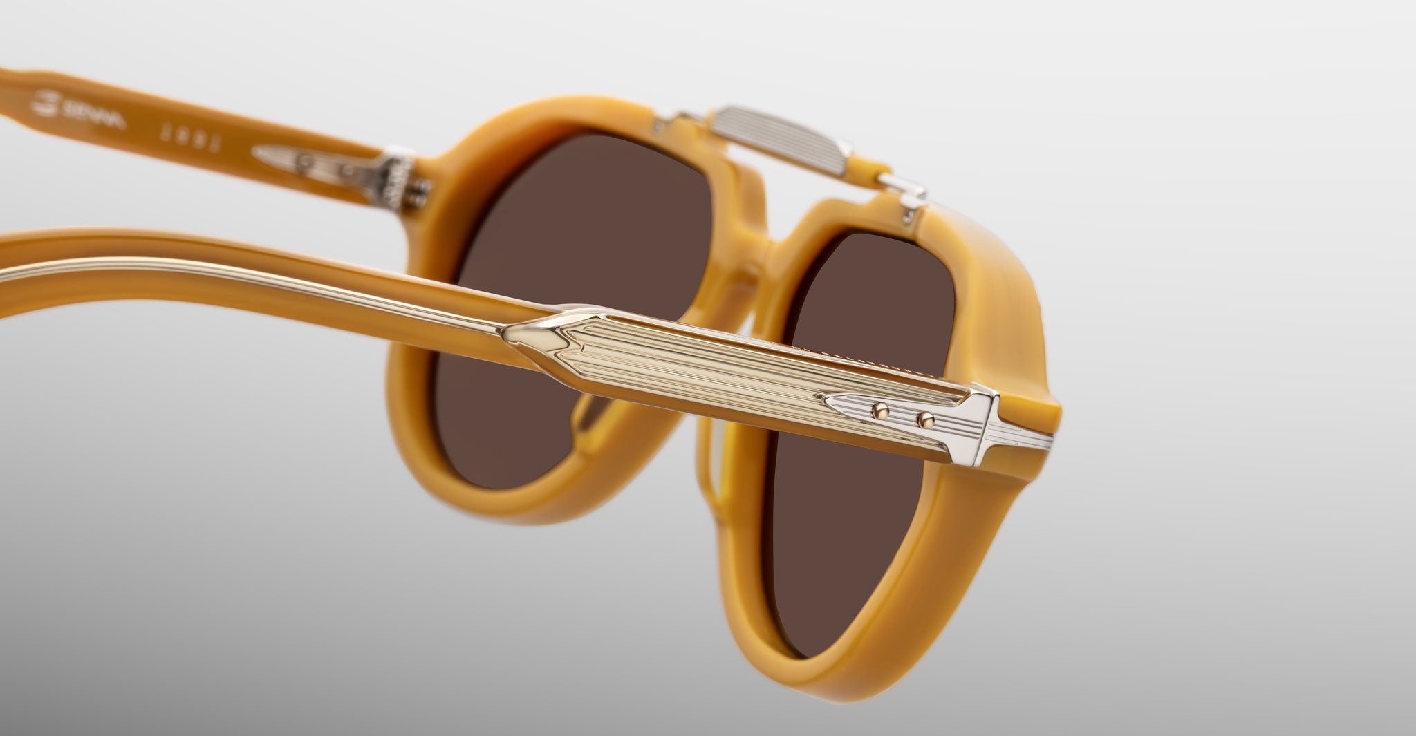 Close-up of Jacques Marie Mage 1991 sunglasses, mustard yellow frame, dark lenses, and metallic accents.