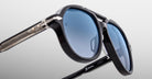 Close-up of Jacques Marie Mage 1991 sunglasses with black frames, blue lenses, and racing text on the inner arm.