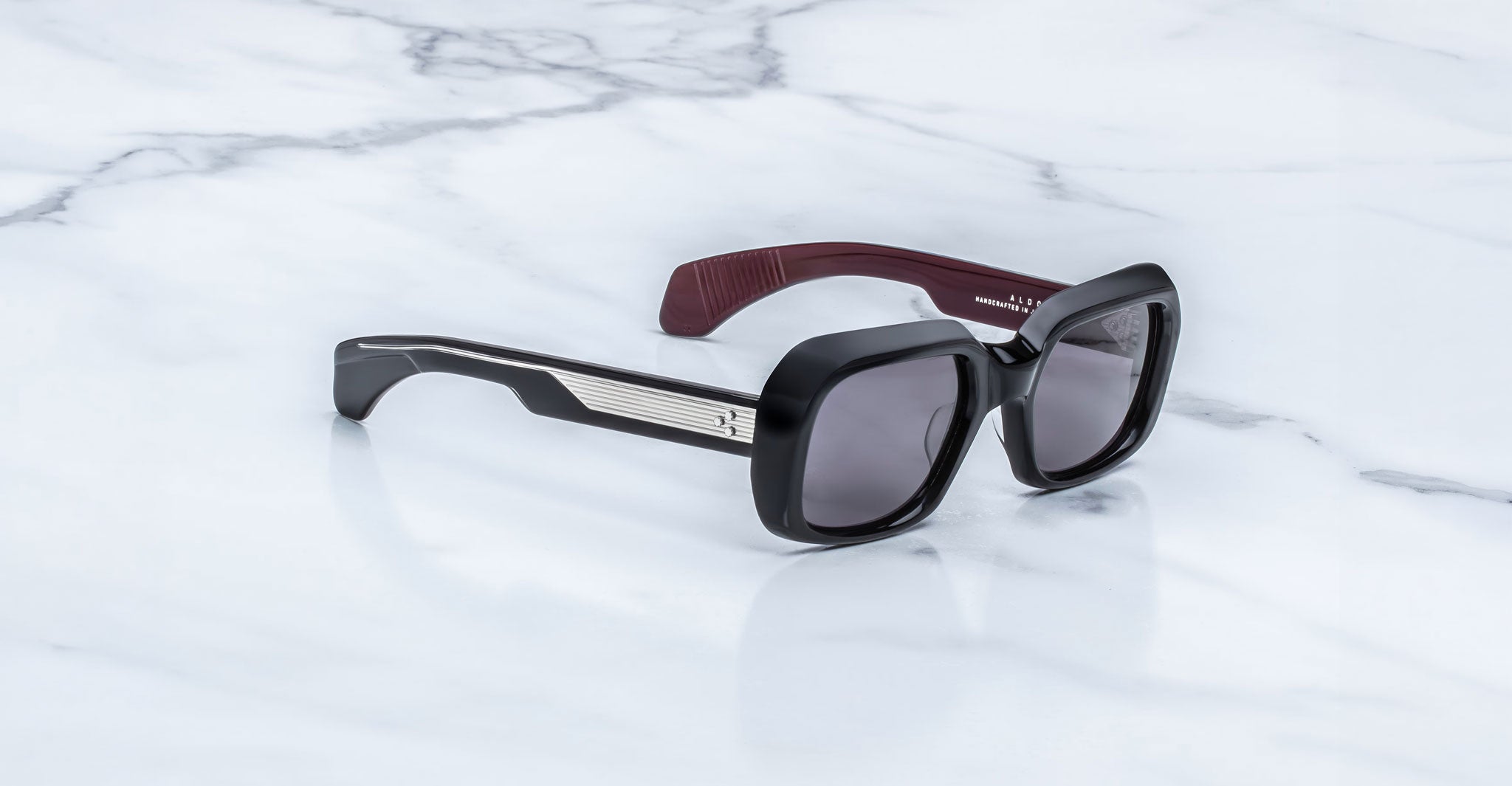 Jacques Marie Mage Aldo sunglasses, black rectangular frames with polarized lenses and metallic accents, front view.