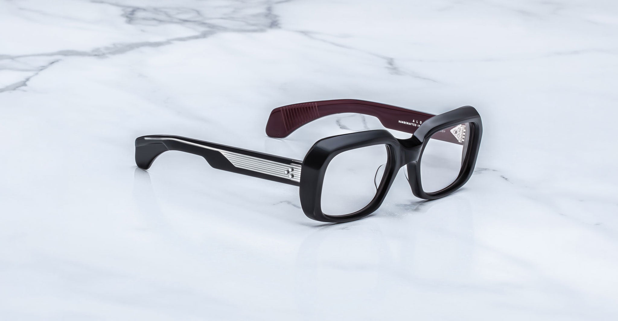 Jacques Marie Mage Aldo black square eyeglasses with maroon inner arms, top-down view.