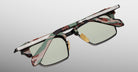 The Jacques Marie Mage Alin eyeglasses feature green-tinted lenses, a camouflage-patterned frame, and a silver metal accent on the top rim, shown against a light gray background.