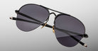 The Jacques Marie Mage Amelia sunglasses feature aviator-style black metal frames, thin arms, and dark tinted lenses, displayed against a plain light gray background.