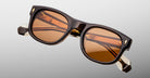 Jacques Marie Mage Amilcar sunglasses, brown acetate frame, amber lenses, gold accents, visible hinges, front view.