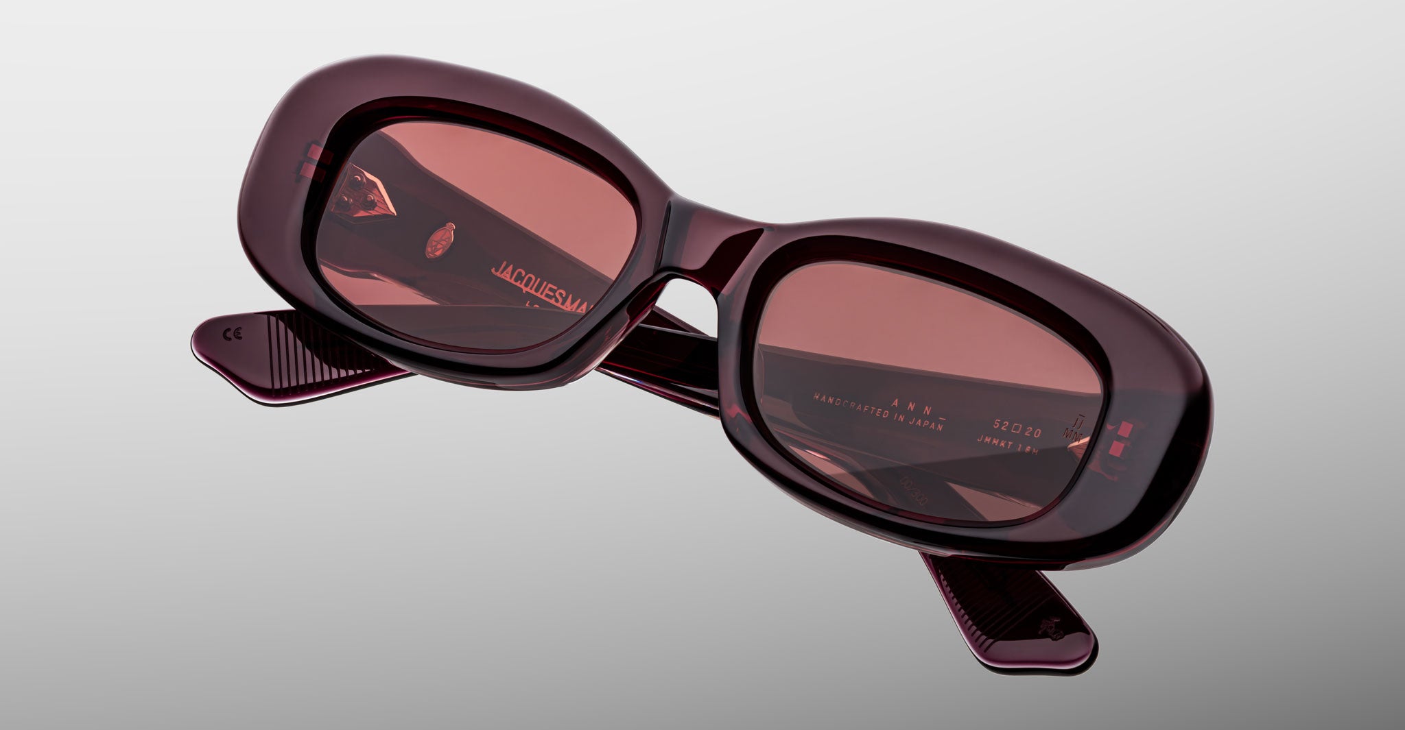 Jacques Marie Mage Ann in Amarena Red, angled view showing translucent burgundy acetate frame and rose-tinted lenses
