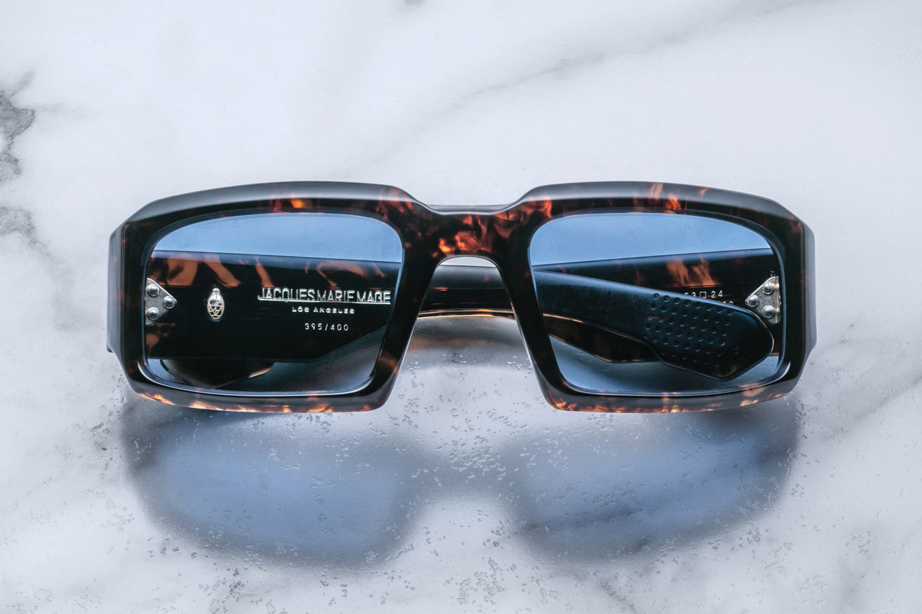 Front view of Jacques Marie Mage Apollo in Agar featuring a bold rectangular frame in dark tortoiseshell acetate, thick sculpted rims, blue-tinted lenses, and hinge hardware visible through the lens.
