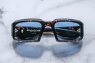 Front view of Jacques Marie Mage Apollo in Agar featuring a bold rectangular frame in dark tortoiseshell acetate, thick sculpted rims, blue-tinted lenses, and hinge hardware visible through the lens.