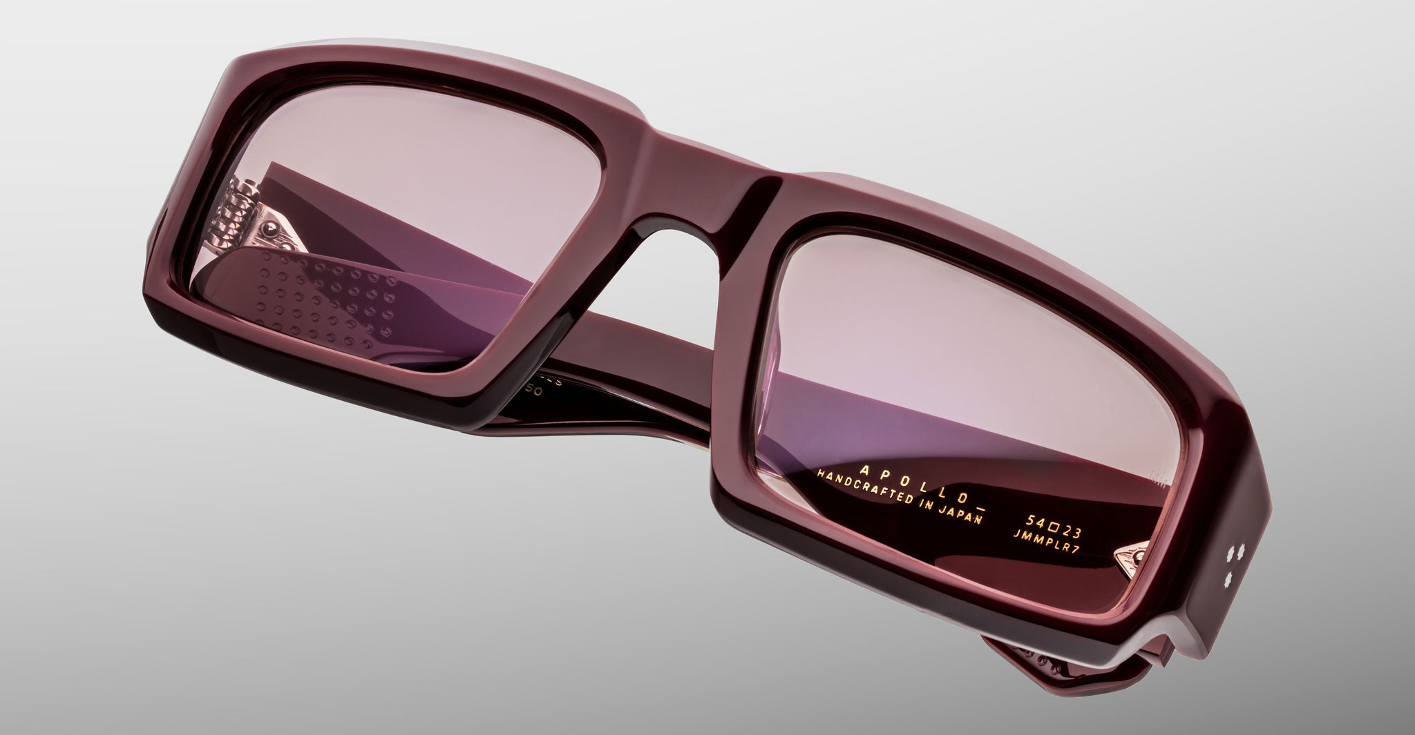 Jacques Marie Mage Apollo in Bordeaux Empire shown in angled view, featuring a bold rectangular frame in deep burgundy acetate, thick sculpted rims, rose-tinted lenses, and wide temples with signature triple dot rivets.