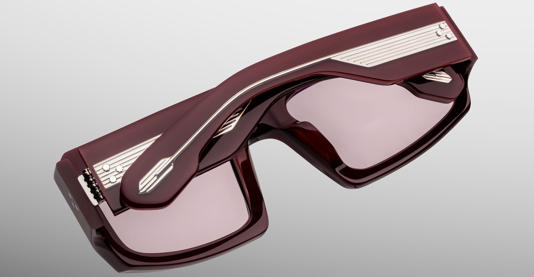 Top angled view of Jacques Marie Mage Apollo in Bordeaux Empire highlighting the deep burgundy acetate frame, beveled rectangular lenses with rose tint, sculpted temples with exposed engraved metal core, and signature arrowhead details.