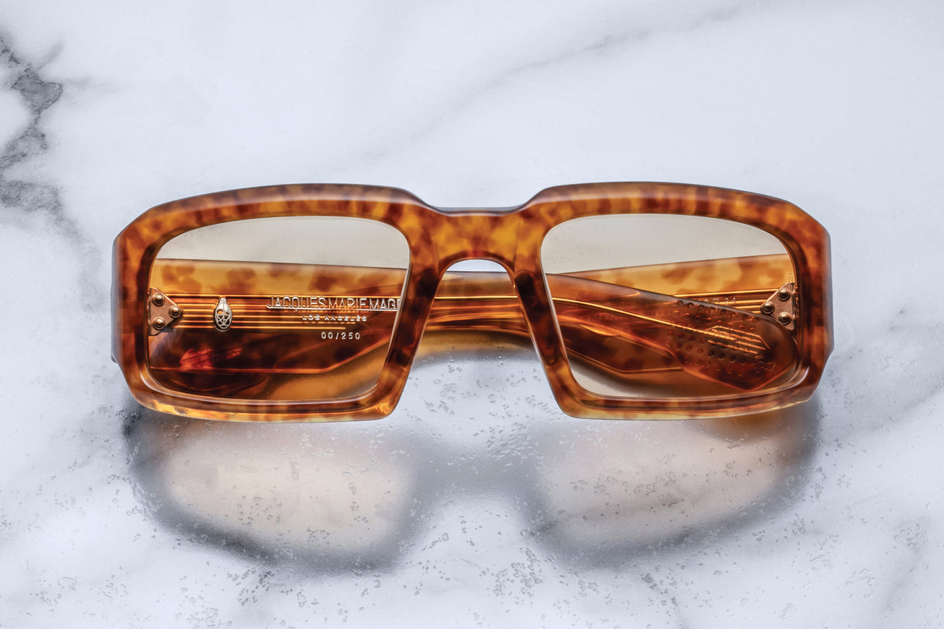 Front view of Jacques Marie Mage Apollo in Camel featuring a bold rectangular frame in warm tortoiseshell acetate, thick sculpted rims, amber-tinted lenses, and metal hinges visible through the lens.