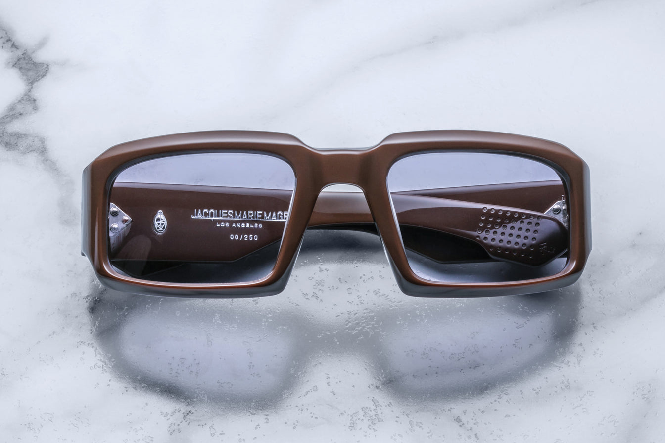 Front view of Jacques Marie Mage Apollo in Chocolate featuring a bold rectangular frame in rich brown acetate, thick sculpted rims, subtle tinted lenses, and signature metal hinge details visible through the lens.
