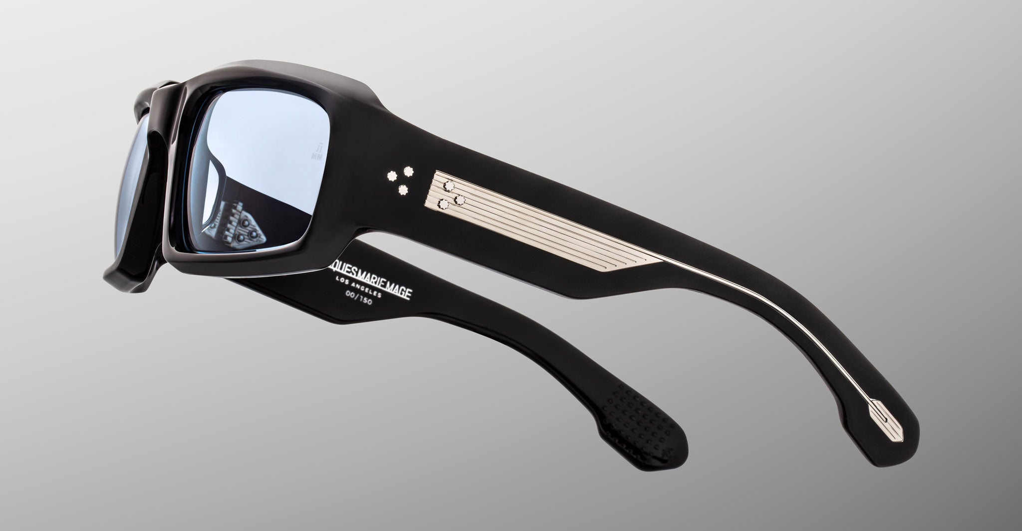 Side view of Jacques Marie Mage Apollo in Shadow featuring a thick black acetate frame with a wide sculpted temple, triple dot rivet detailing, exposed metal core with fine line engraving, signature arrowhead tip, and blue-tinted lens.