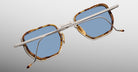 Jacques Marie Mage Atkins sunglasses with rectangular tortoiseshell frames, blue lenses, thin silver arms; overhead view.