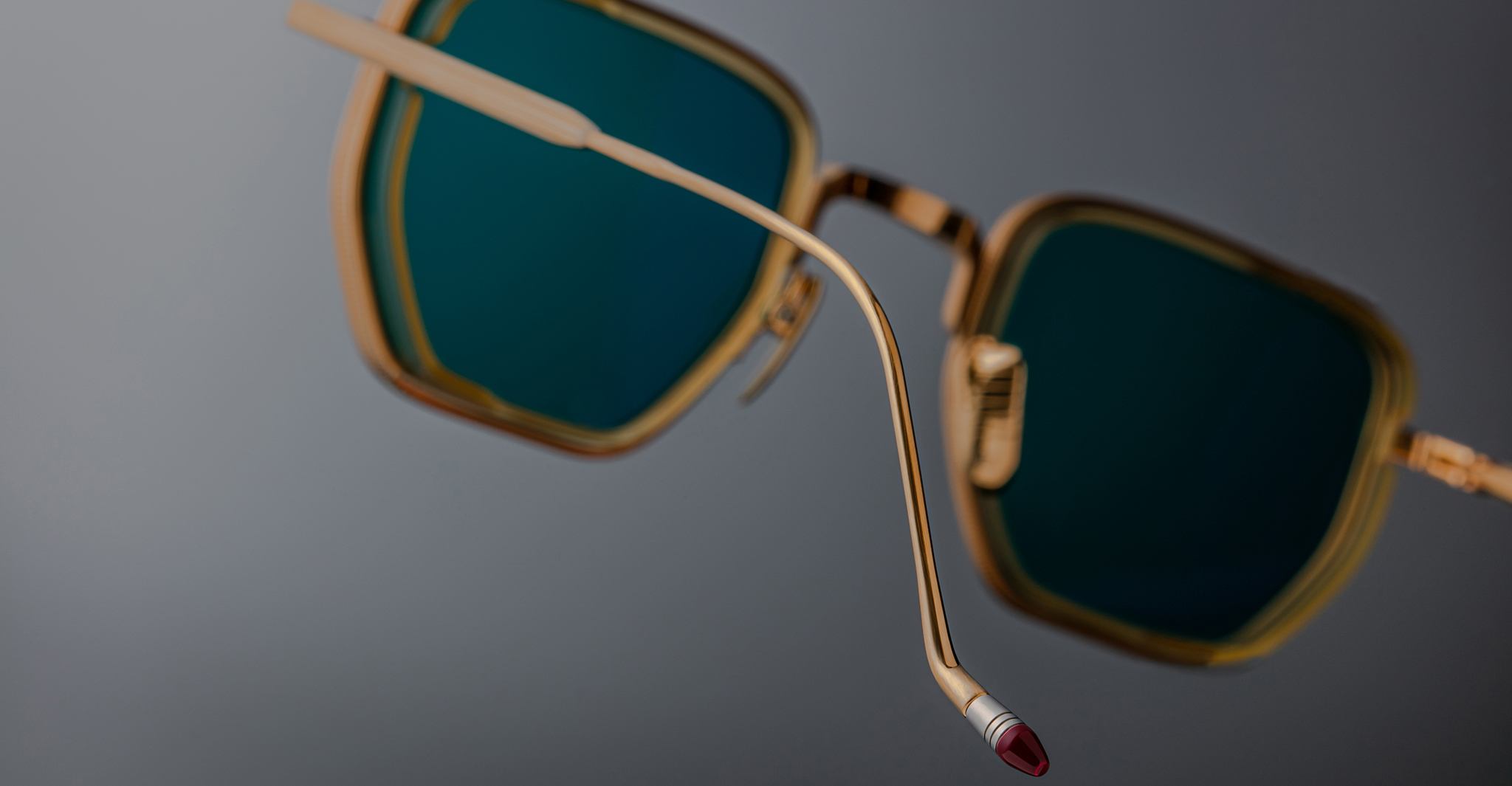 Close-up of Jacques Marie Mage Atkins sunglasses, gold frame and green lenses, side view focusing on the temple arm.