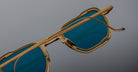 Jacques Marie Mage Atkins gold aviator sunglasses with blue lenses, shown in a close-up angled view.