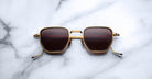 Jacques Marie Mage Atkins square sunglasses with gold frames and dark lenses, top view.