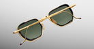 The Jacques Marie Mage Atkins sunglasses, with gold rectangular frames and dark green lenses, are displayed from the back against a gray background, showcasing their handcrafted Japanese quality with crossed temples.