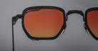 Close-up of Jacques Marie Mage Atkins geometric black sunglasses with orange-tinted lenses, shown from the front angle.