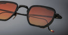 Jacques Marie Mage Atkins sunglasses, black square frame, orange-tinted lenses, gold accents, shown from the front angle.