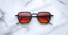 Jacques Marie Mage Atkins square sunglasses with red gradient lenses, shown from above.
