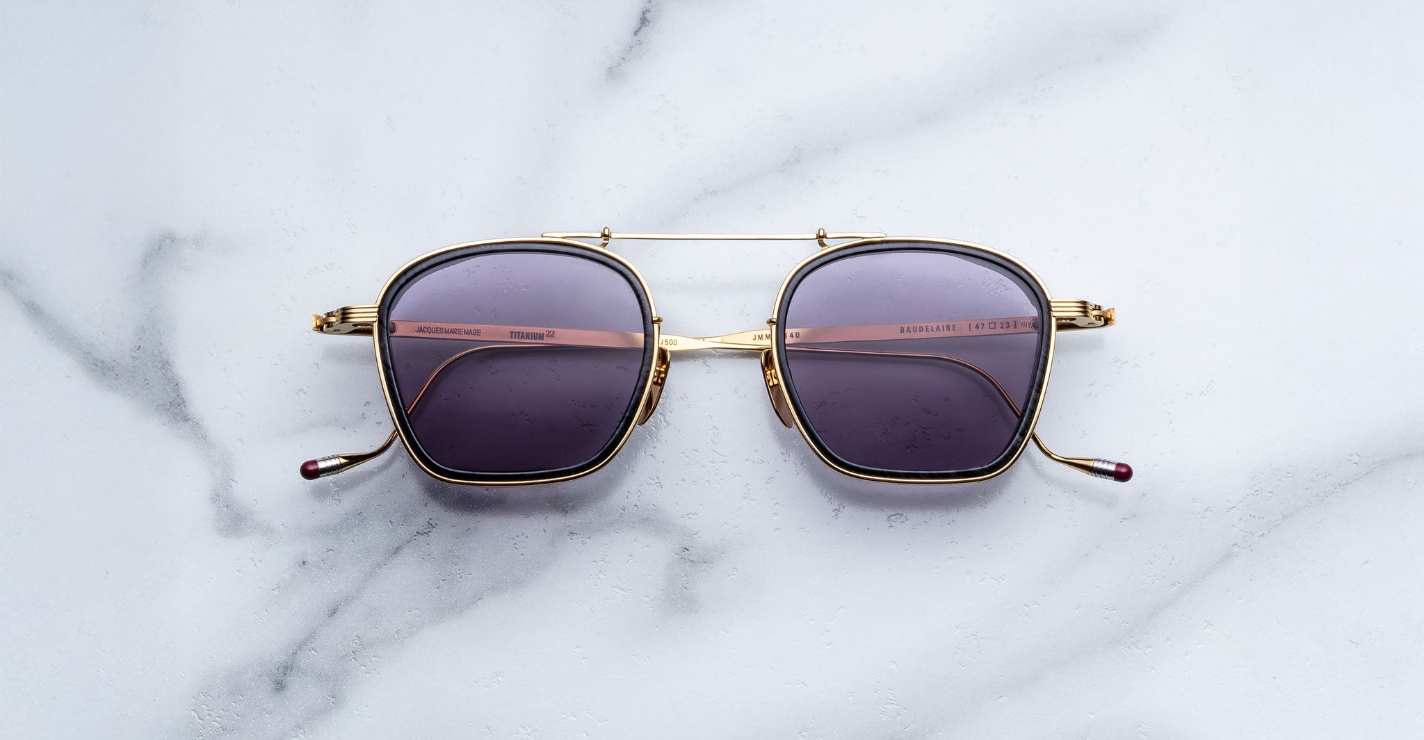 Jacques Marie Mage Baudelaire 2 gold square sunglasses with dark lenses, top-down view.