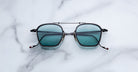 Jacques Marie Mage Baudelaire 2 sunglasses with black frames and blue lenses, top view.