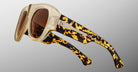 The Jacques Marie Mage Bel Air sunglasses feature translucent beige handcrafted acetate frames, brown lenses, thick arms with a bold tortoiseshell pattern, and silver detailing, set against a gradient gray background.
