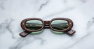 Jacques Marie Mage Besset brown oval sunglasses with green UV-protective lenses, top view.