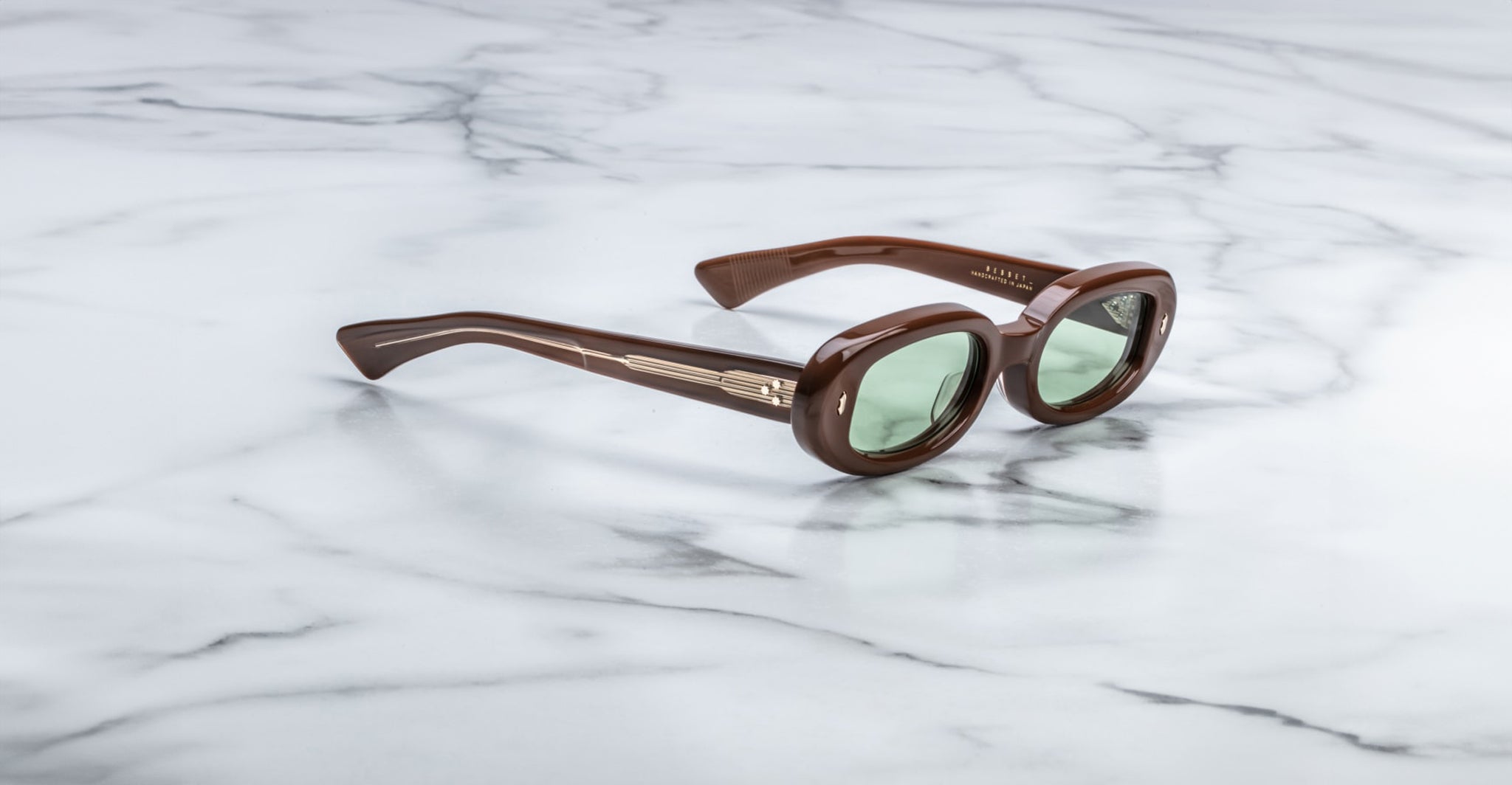 Jacques Marie Mage Besset brown oval sunglasses with green lenses, front view.