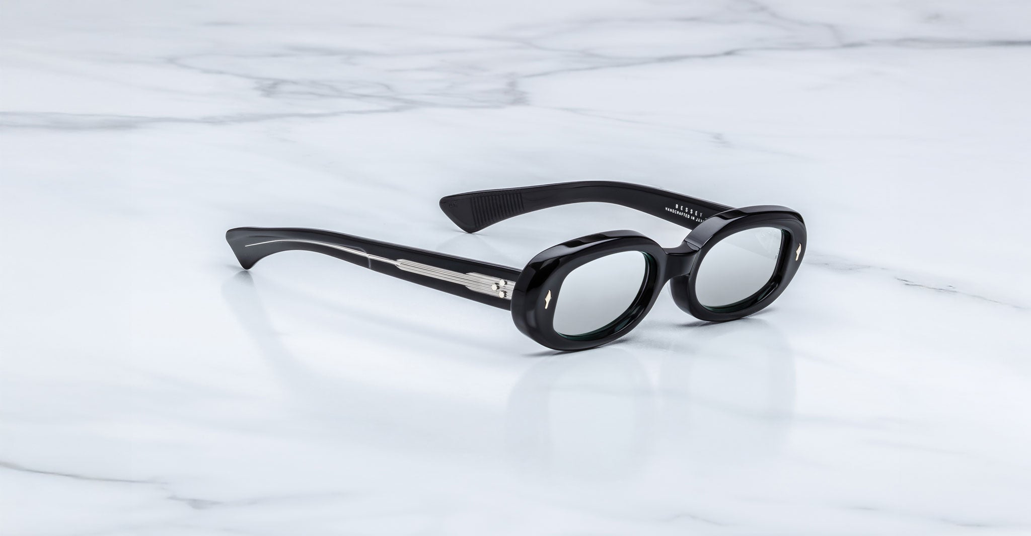 Jacques Marie Mage Besset black oval sunglasses with thick frames and silver accents, top view.