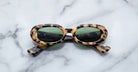 Jacques Marie Mage Besset tortoiseshell oval sunglasses with green lenses, seen from above.
