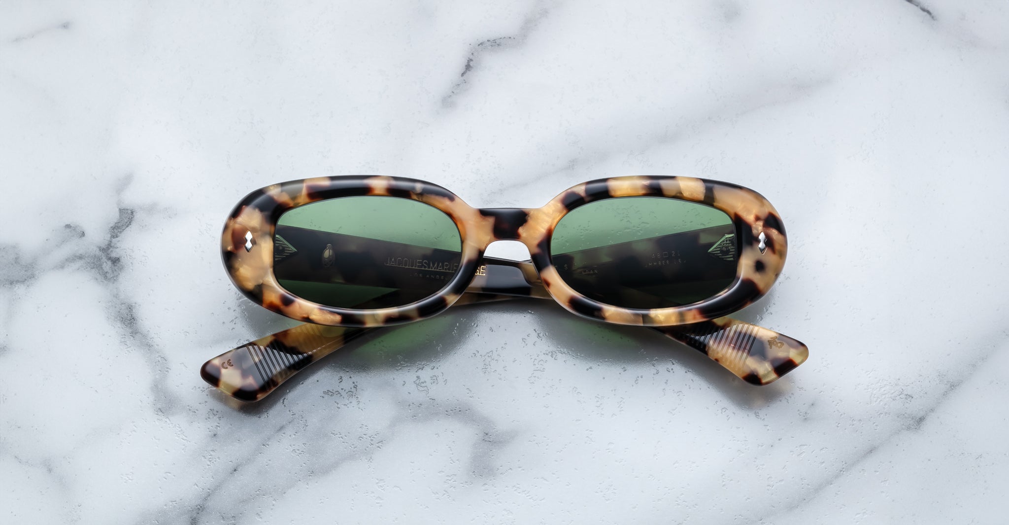 Jacques Marie Mage Besset tortoiseshell oval sunglasses with green lenses, seen from above.