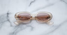 Jacques Marie Mage Besset beige oval sunglasses with brown UV-protective lenses shown from above.